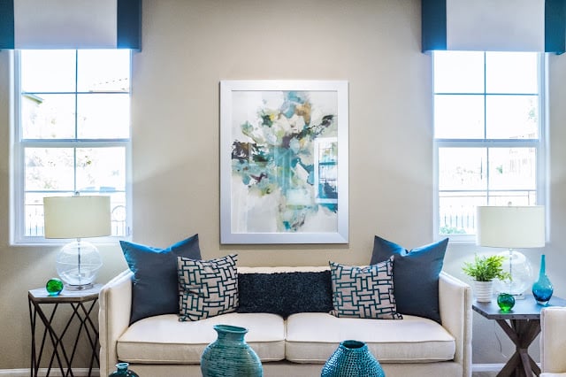 A cream sofa with teal cushions