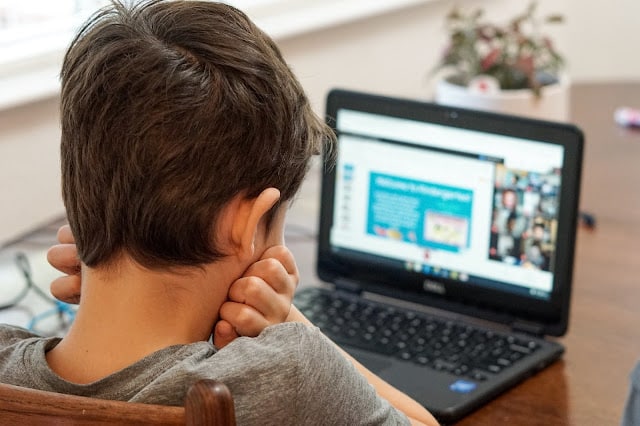 A child looking on the internet on a black laptop