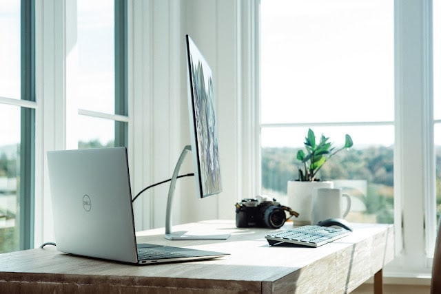 A home office set up consisting of a computer sat on a desk in front of the window