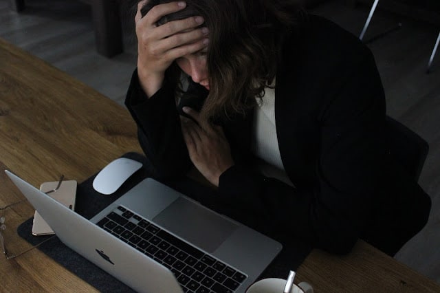 woman sat at a laptop with her head in her hands