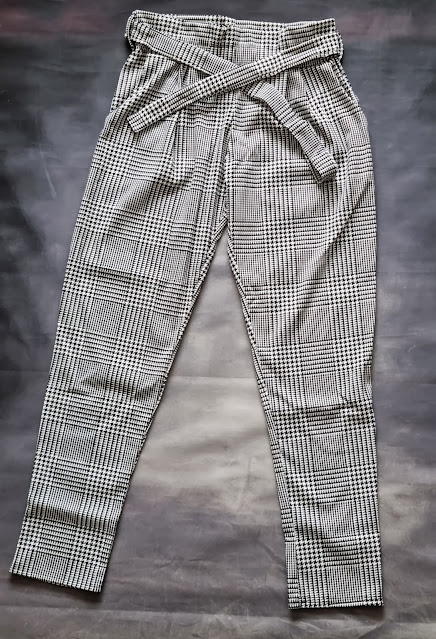 High-waisted, black-and-white check trousers with a matching fabric belt—one of our September fashion Femmeluxe favourites. The trousers feature a tapered leg, pleated waist, and are displayed flat on a dark background.