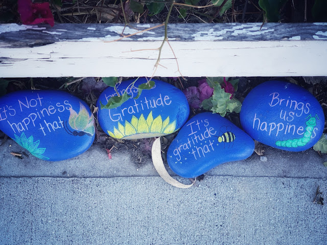 A number of rocks painted blue with positive words written on them