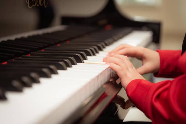 a child in a red jumper playing the piano