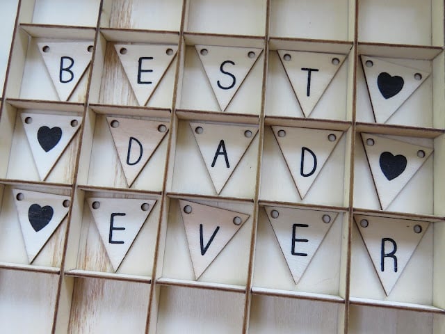 Wooden triangular tiles arranged in a grid spell out "BEST DAD EVER," with black heart symbols replacing two "A"s—a thoughtful touch perfect for Last Minute Father's Day Gift Ideas.