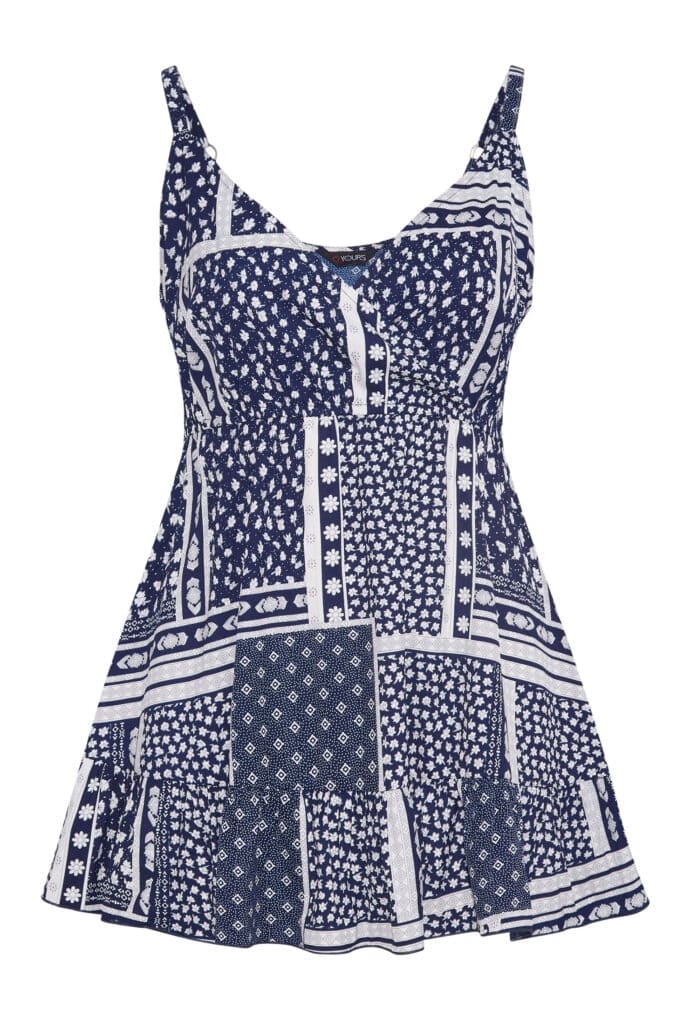 Your clothing collection shines with this sleeveless navy blue and white sundress, featuring a patchwork pattern of florals and geometric shapes, a fitted bodice, flared skirt, and thin shoulder straps.