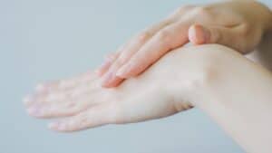 Close-up of a person gently touching the back of one hand with the other, showcasing neatly manicured nails and smooth, fair skin—perfect inspiration for How To Upgrade Your Skincare Routine As A Busy Mum.