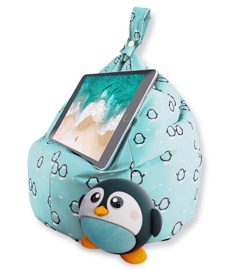 A tablet rests on a light blue Planet Buddies beanbag with a penguin pattern. In front of the beanbag is a small, round penguin figurine with big eyes and orange feet.