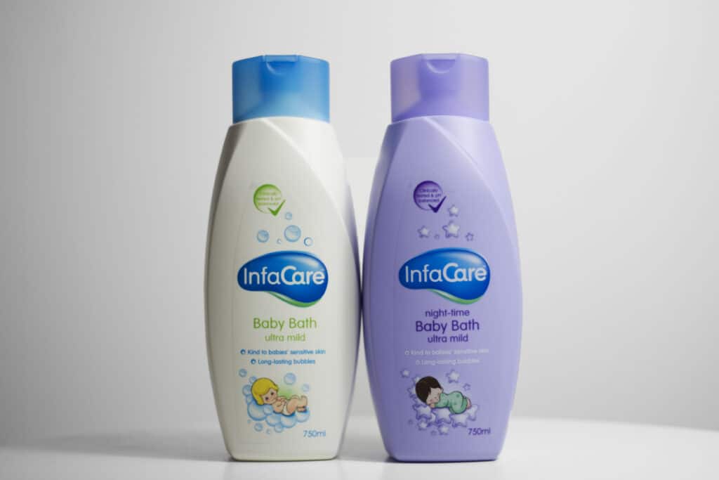 Two Infacare products stand side by side: the white bottle with a blue cap labelled "Baby Bath ultra mild", and the purple bottle with a lavender cap labelled "Night-time Baby Bath ultra mild.