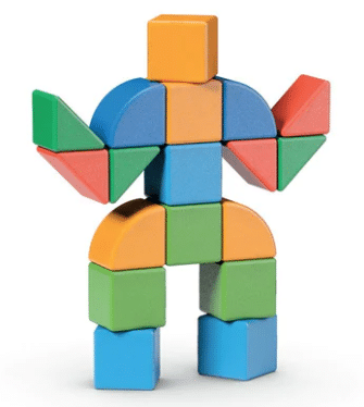 A figure resembling a person made from colourful geometric wooden blocks, including rectangles, squares, triangles, and arches in blue, green, orange, and red—arranged upright like a playful Geomag Magicube creation on a white background.