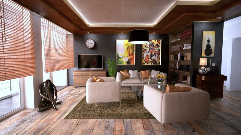 Modern living room with wooden floors, beige sofas, a large rug, TV, bookshelves, wall art, a clock, flowers on a table, and large windows with wooden blinds—perfect for adding more comfort into your home with natural light.
