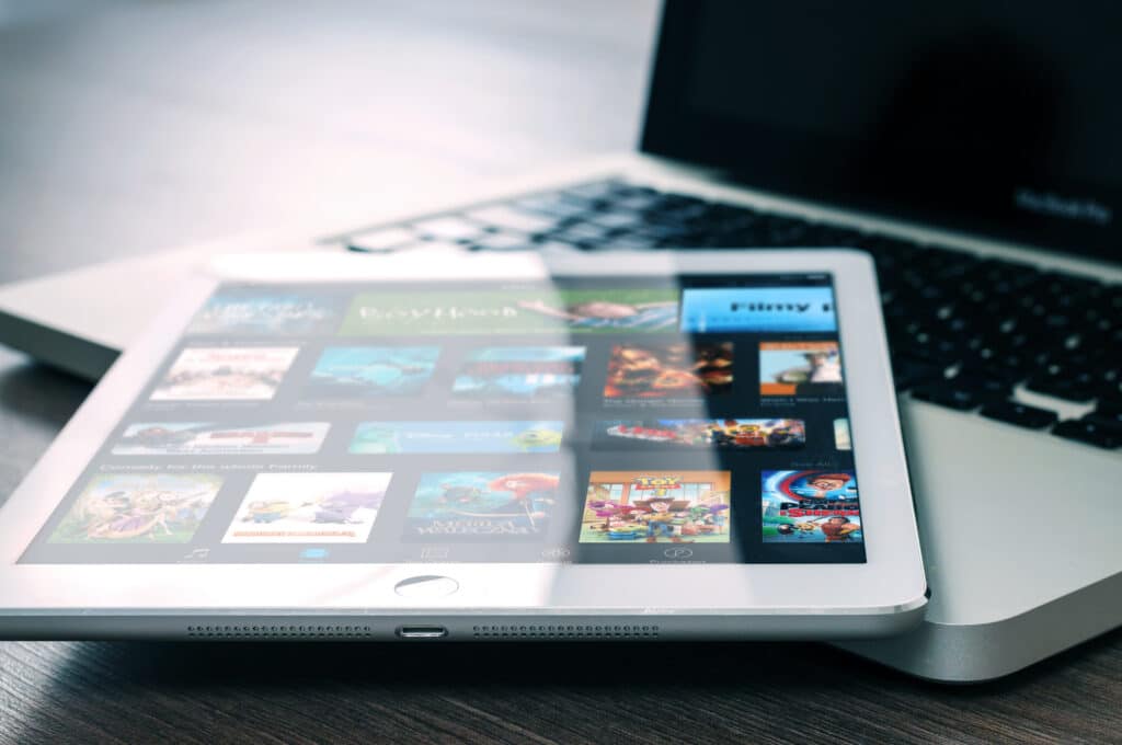 An ipad sat on top of an open but switched off laptop