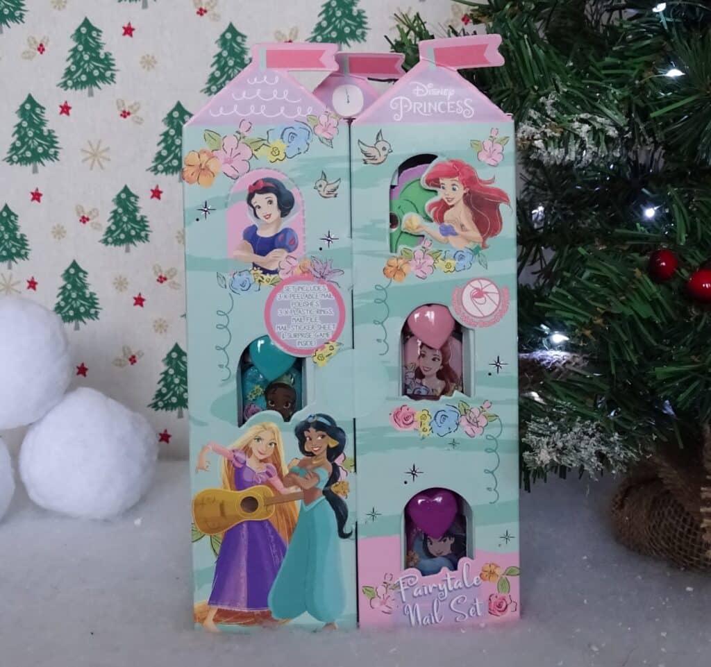 A Disney Princess Advent calendar with princess illustrations and open windows revealing small toys, placed by a decorated Christmas tree and snowball decorations. A festive tree pattern completes this magical Christmas Gift Idea for Children 2022.