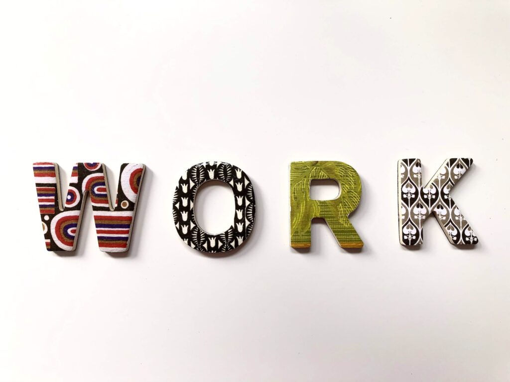 The word "WORK" spelt out in large, decorative letters, each with a different colourful pattern representing various professions, placed on a plain white background.