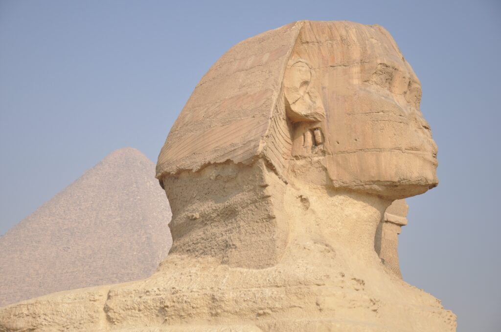 Side view of the Great Sphinx of Giza, with the Pyramid of Khafre in the background under a clear blue sky—making you wonder, Are The Pyramids Really Worth Adding To Your Travel Bucket List?.