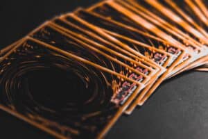 A fanned-out stack of Yu-Gi-Oh! trading cards displayed on a dark surface, showing their signature swirling orange and black card backs.
