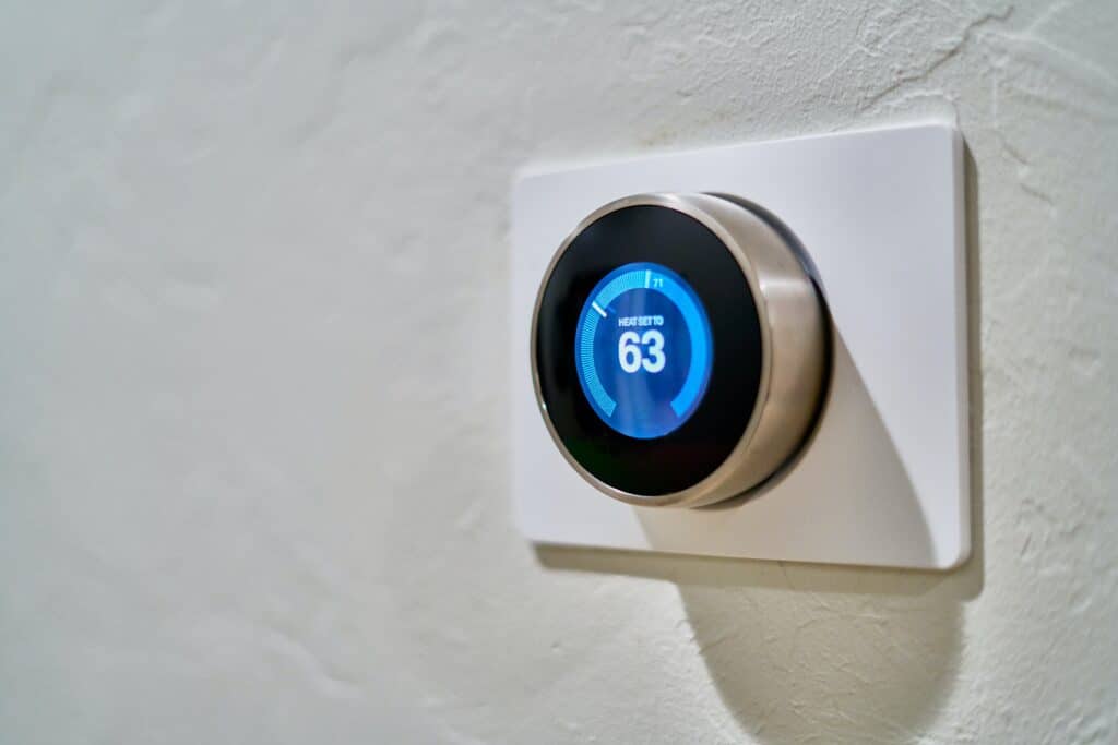 A smart thermostat, part of a recent HVAC system installation in Canoga Park, is mounted on a white textured wall and displays a temperature setting of 17 degrees.