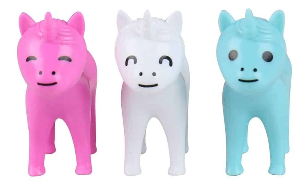 Three toy unicorns are lined up side by side: one pink with closed eyes, one white with smiling closed eyes, and one light blue with open eyes. All have simple, cartoon-like features—a must-have for anyone who loves unicorn and dinosaur toys.