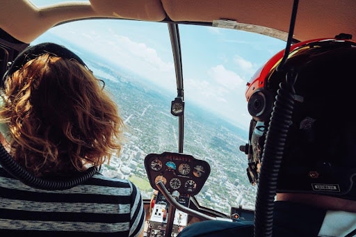 two people sat in the front of a helicopter whilst it is flying