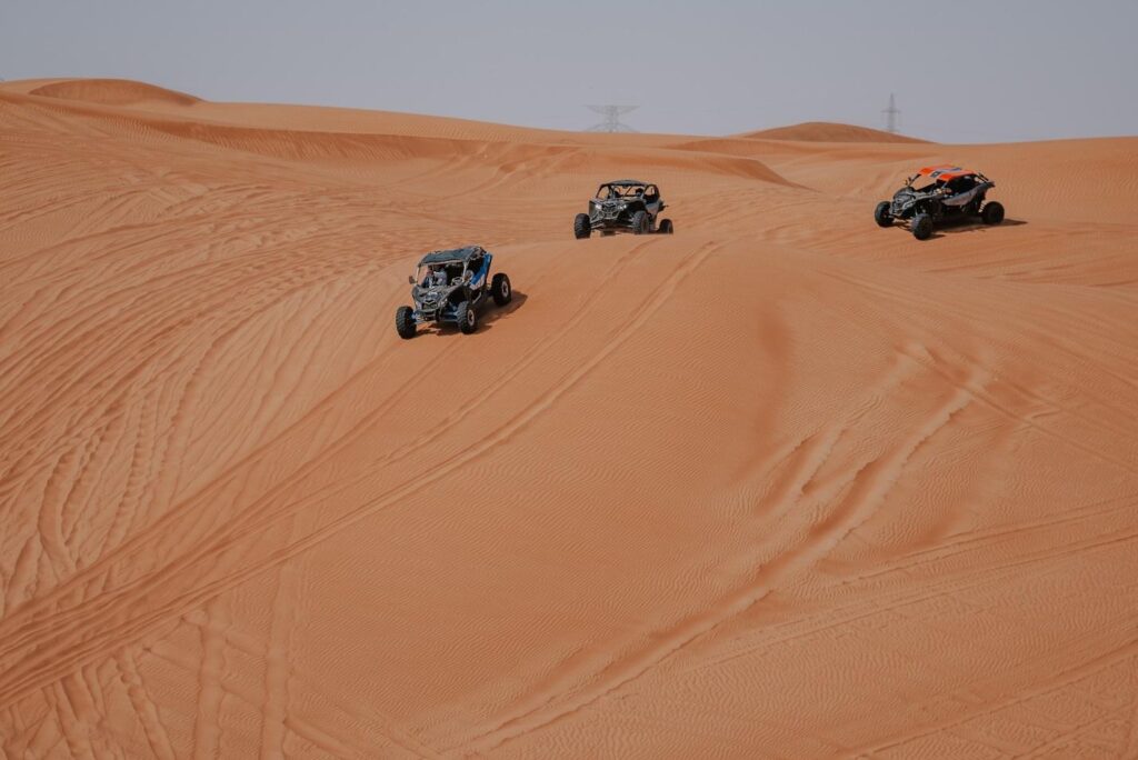 Three dune buggies racing in the desert in Dubai.