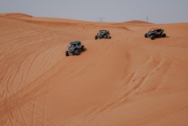 Three dune buggies racing in the desert in Dubai.