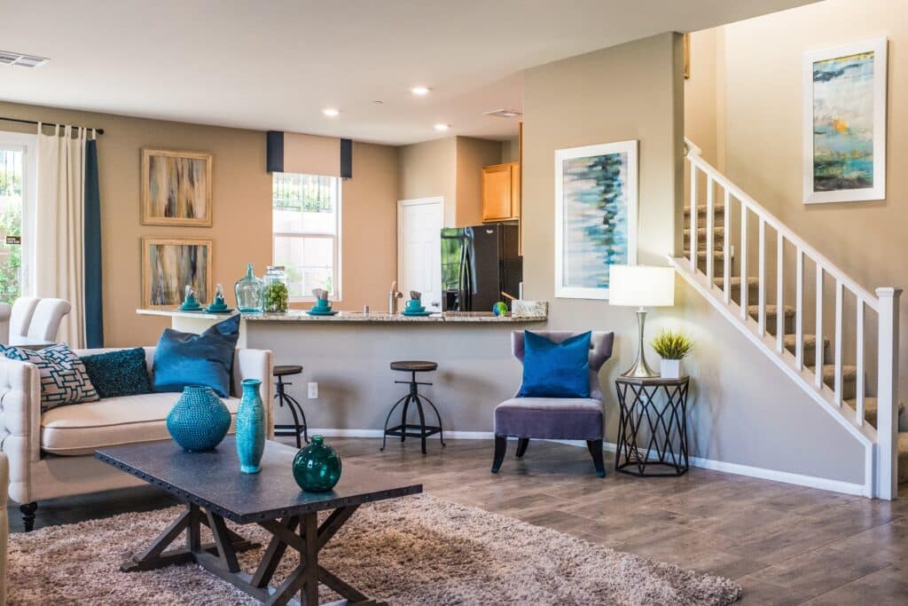 A living room with sofa and settee near an open stair case