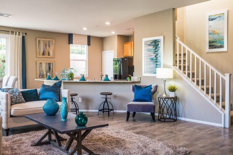 A living room with sofa and settee near an open stair case