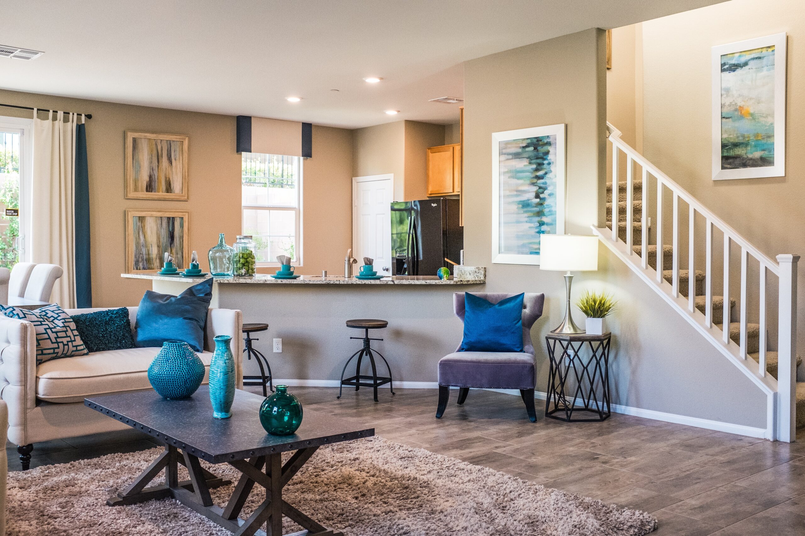 A living room with sofa and settee near an open stair case
