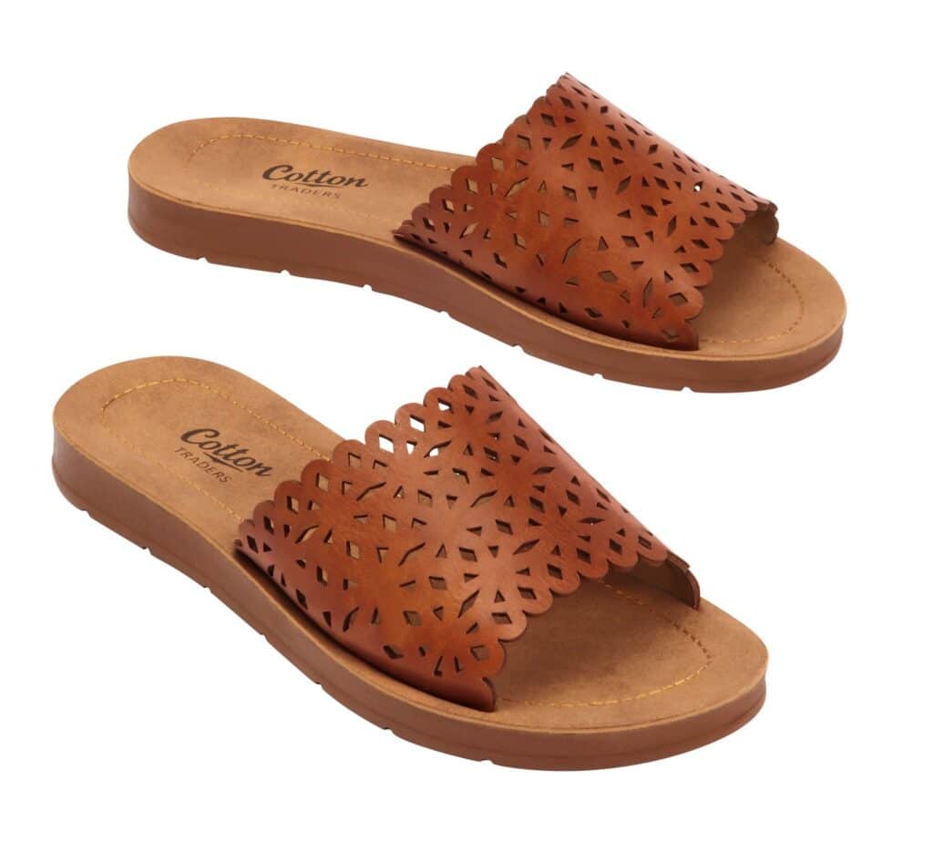 A pair of brown slip-on sandals with laser-cut floral patterns on the wide straps and cushioned soles, bringing comfortable clothing to your everyday style, displayed on a white background.