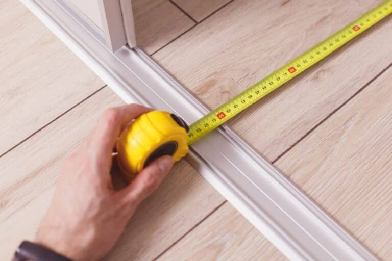 A man measuring the space for a wardrobe on a light wooden floor