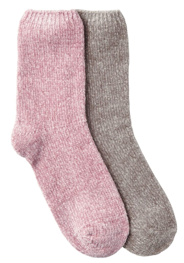 Two pairs of thick, ribbed knitwear socks are displayed side by side; one pair is light pink and the other is light grey. Both pairs appear soft and cosy, likely made from a plush, fuzzy material.