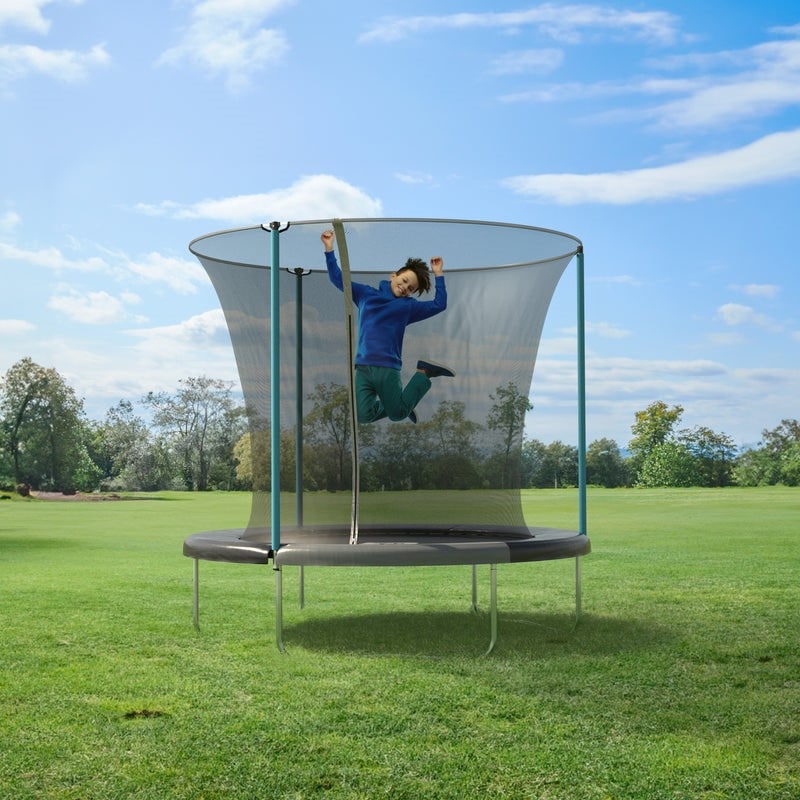 A person in a blue shirt and green trousers jumps joyfully on a trampoline with a safety net, set in a large grassy field under a blue sky—an ideal scene for fostering childhood development.