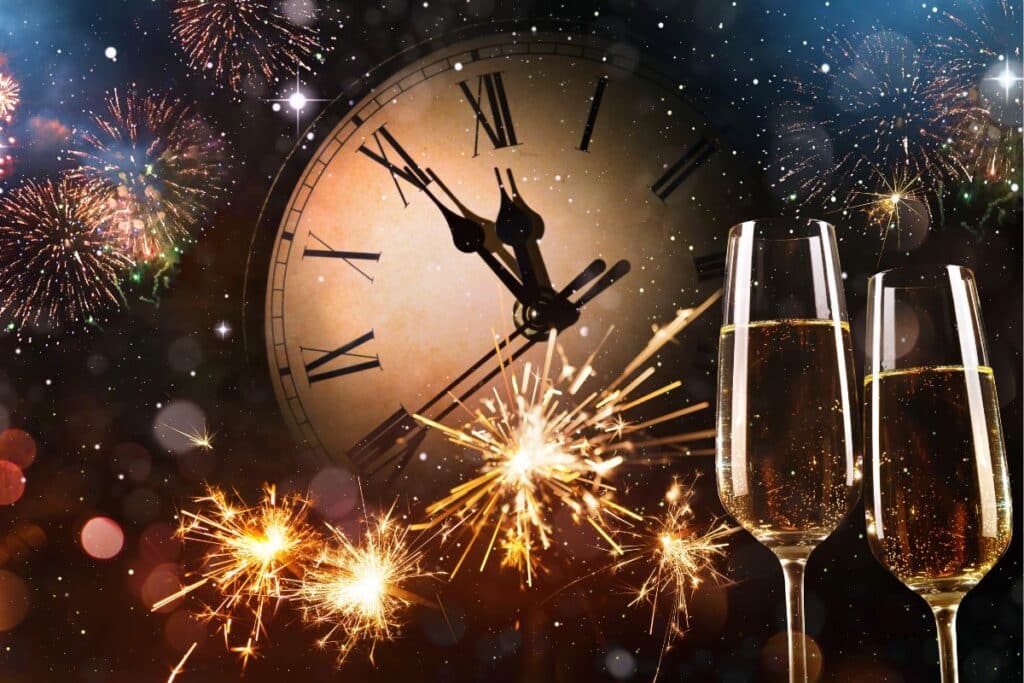 A festive New Year’s scene with fireworks, sparklers, a large clock nearing midnight, and two champagne glasses filled with fizzy in the foreground—perfect for celebrating New Year’s Eve Bristol-style.
