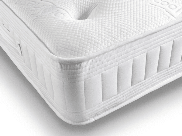 A close-up view of the corner of a white mattress with a textured, quilted surface and stitched side panels—ideal comfort for warmer sleepers.