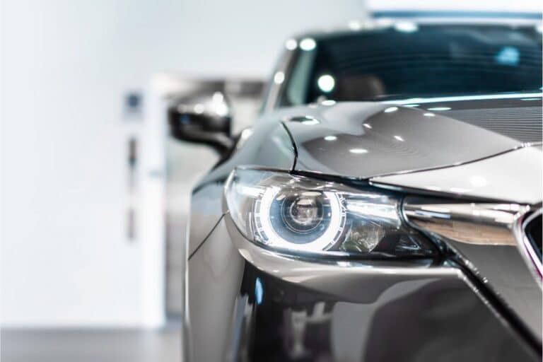 Close-up view of the front left headlamp and part of the grille of a modern silver car, featuring a sleek and shiny exterior indoors with a blurred background—captured exclusively for Reclaim247.