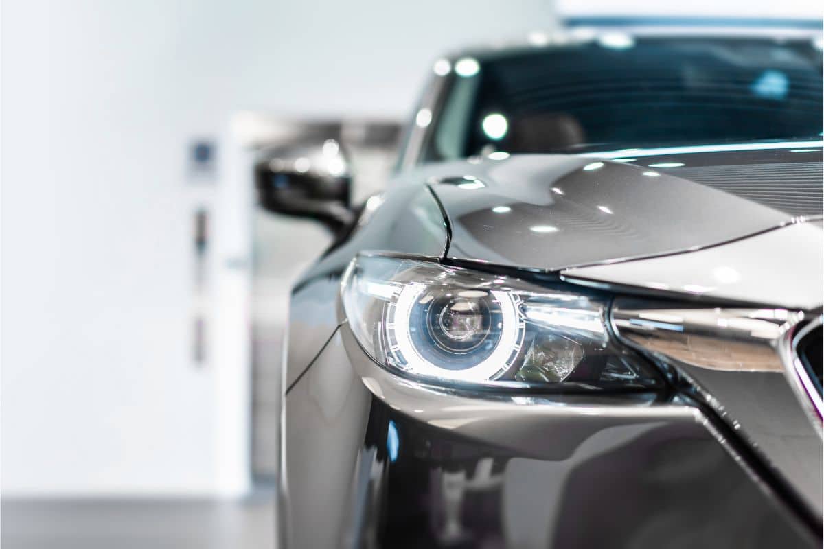 Close-up view of the front left headlamp and part of the grille of a modern silver car, featuring a sleek and shiny exterior indoors with a blurred background—captured exclusively for Reclaim247.