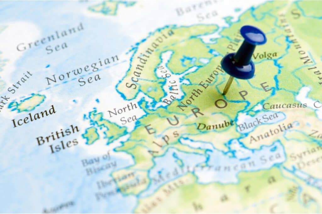 A close-up of a weather map of Europe with a blue drawing pin marking a central location on the continent; surrounding regions like the British Isles, Scandinavia, and Anatolia are also visible.