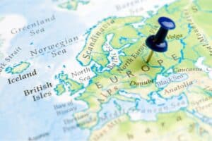 A close-up of a weather map of Europe with a blue drawing pin marking a central location on the continent; surrounding regions like the British Isles, Scandinavia, and Anatolia are also visible.