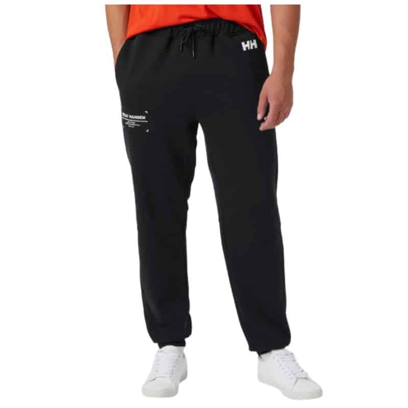 A person wearing black jogger sweatpants with white text details, a red shirt, and white trainers stands against a plain white background—perfect for a relaxed Father’s Day look.