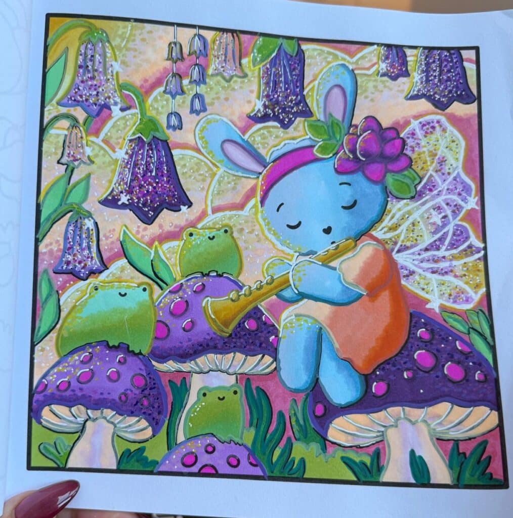 A blue bunny with fairy wings and a flower crown plays a flute whilst sitting on a purple mushroom, surrounded by frogs, glowing bell-shaped flowers, and vibrant, magical scenery—perfect for a whimsical colouring adventure.