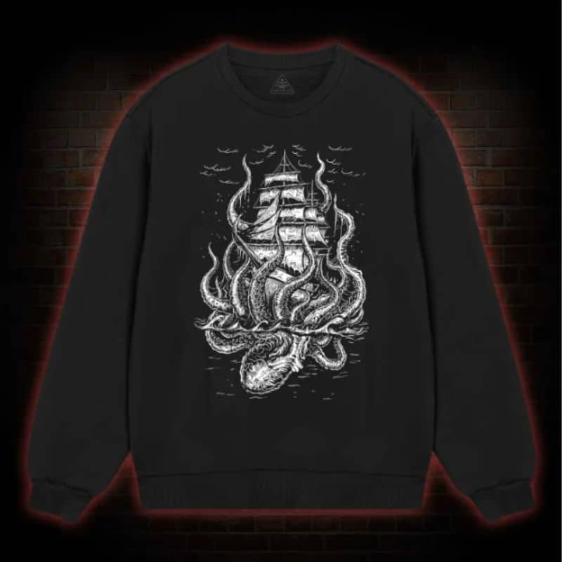 A black sweatshirt features a white, detailed illustration of a sailing ship hilariously entangled by a giant kraken, adding a touch of dark humour as birds fly in the background. The bold design is centred on the front.