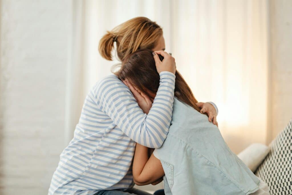 a mother hugging her teenage child who is upset