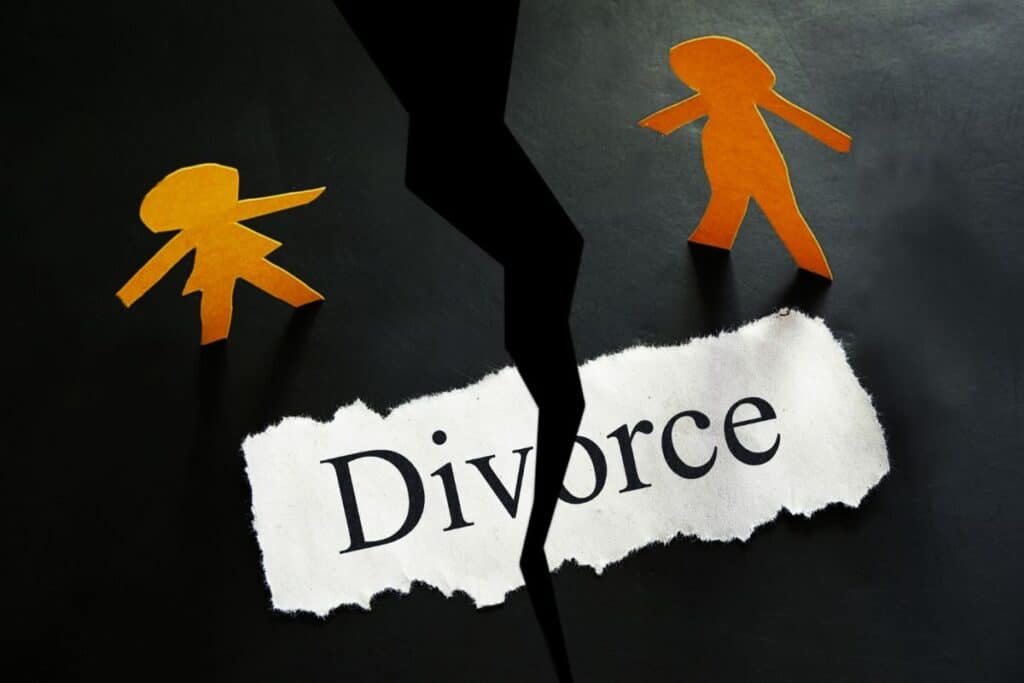 Two orange paper cut-outs of people are separated by a jagged black tear, with "Divorce" on ripped paper between them, symbolising the impact of divorce on children and the emotional divide often felt by teenagers.