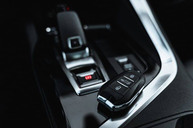 A close-up of a car’s centre console featuring a gear lever and key fob with lock, unlock, and boot buttons—everyday car accessories that let you personalise your car. The sleek black interior is accented with modern silver details.