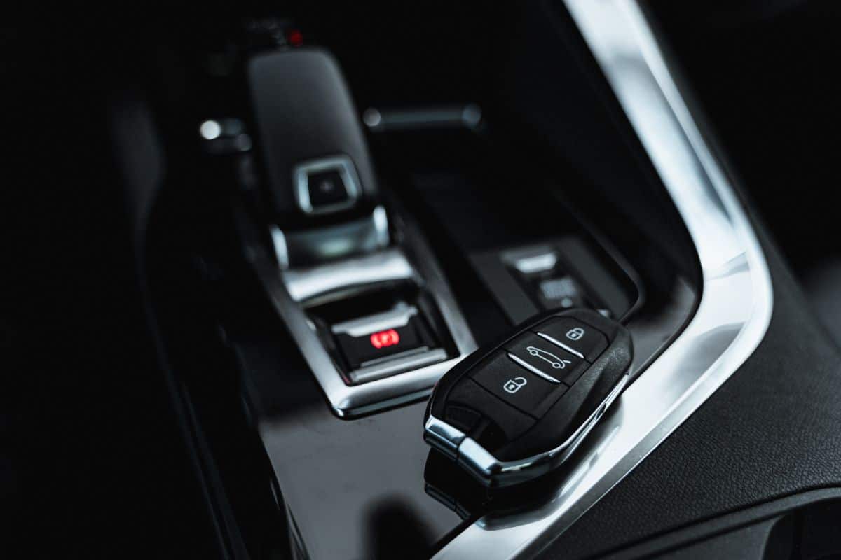 A close-up of a car’s centre console featuring a gear lever and key fob with lock, unlock, and boot buttons—everyday car accessories that let you personalise your car. The sleek black interior is accented with modern silver details.
